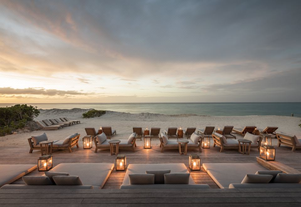 a large deck overlooking the ocean , with rows of chairs and umbrellas set up for a relaxing atmosphere at Como Parrot Cay