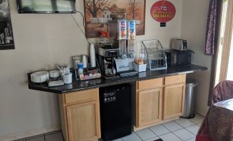 a kitchen counter with various appliances and coffee makers , including a refrigerator , microwave , and coffee maker at Relax Inn