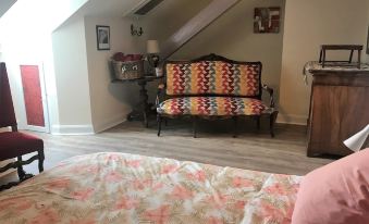 a cozy living room with a couch , bed , and rug on the floor , connected to a bedroom with a wooden headboard at La Roseraie