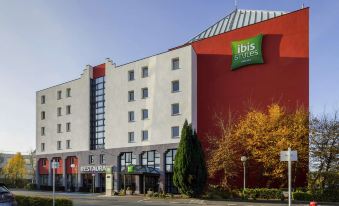 a large hotel building with a red and white facade , located in a city setting at Ibis Styles Lille Marcq-en-Baroeul