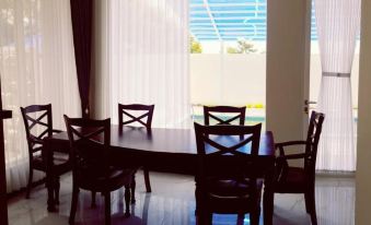 a dining room with a wooden table and four chairs , along with a window providing natural light at Villa Orlando