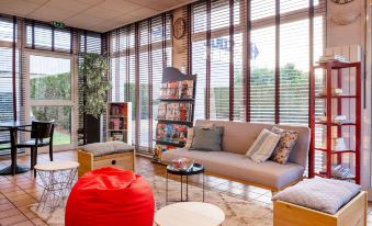 a modern living room with a large window , red bean bag chair , and a beige couch at Comfort Hotel Montlucon