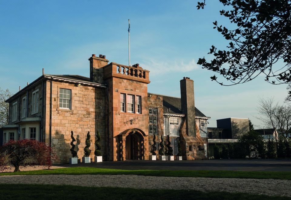 a large brick building with a flag on top , situated in front of a clear blue sky at Dalmeny Park House Hotel