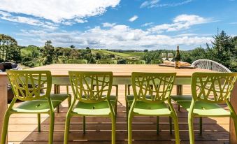 a wooden deck overlooking a beautiful landscape , with several green chairs arranged around a dining table at Vineyard Views