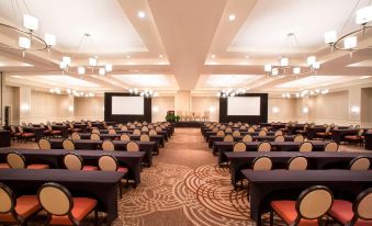 a large conference room with rows of tables and chairs , a projector screen , and a chandelier at Sheraton Orlando North Hotel
