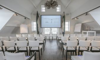 a large conference room with rows of chairs arranged in a semicircle , and a projector mounted on the wall at Fletcher Hotel - Restaurant Nautisch Kwartier
