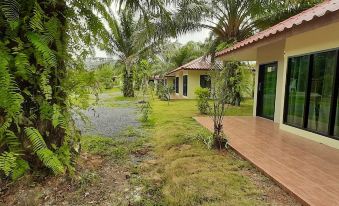 a house with a wooden deck and green door is surrounded by palm trees and grass at Payabangsa Resort