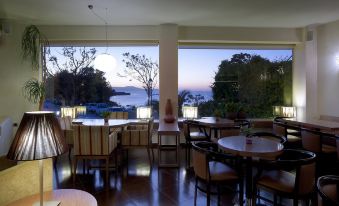 a large dining room with multiple tables and chairs , offering a view of the ocean at Irida