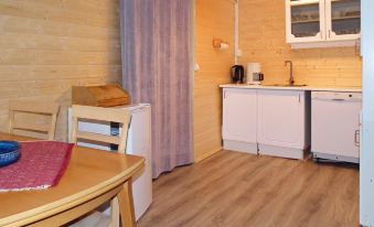 a small kitchen with wooden flooring , white cabinets , and appliances such as a refrigerator , microwave , and sink at Helgeland