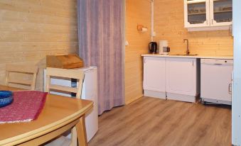 a cozy kitchen and dining area with wooden flooring , white cabinets , and a red tablecloth at Helgeland