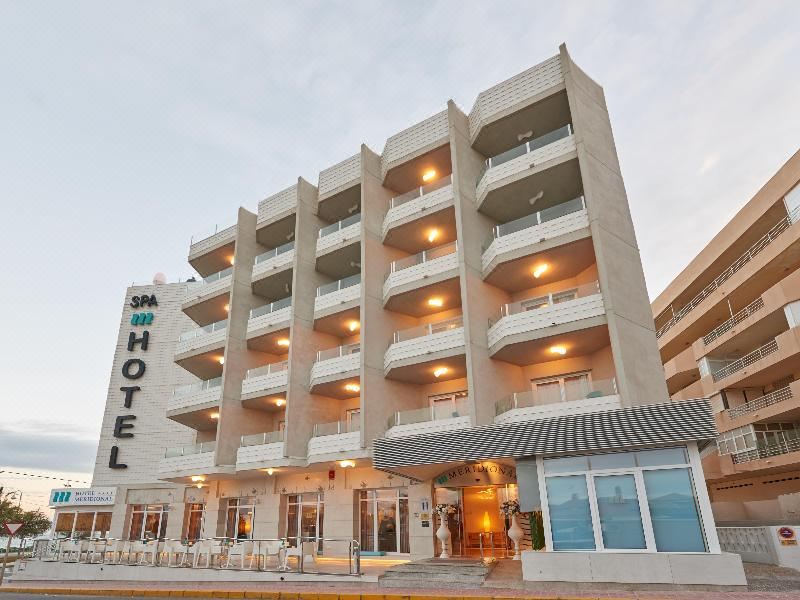 a large hotel building situated on the side of a street , surrounded by cars and people at Hotel Meridional