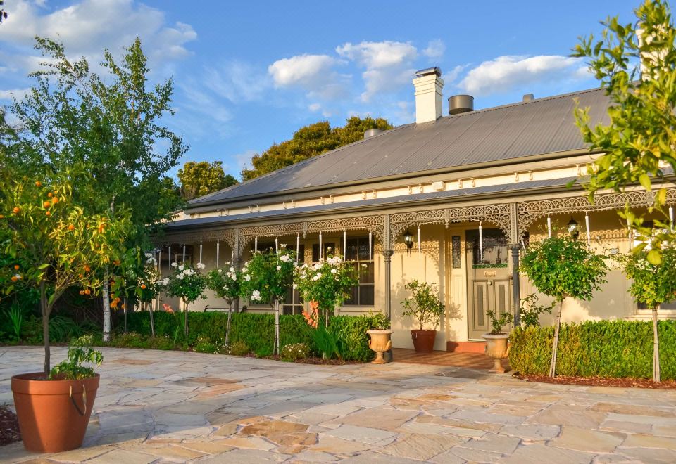 a large house with a gray roof and white columns is surrounded by greenery , including trees and bushes at Brooklands of Mornington