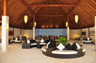 a large , open room with a high ceiling and a row of black and white couches arranged around them at Vilamendhoo Island Resort & Spa