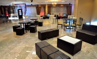 a large , empty banquet hall with numerous black leather couches and chairs arranged in rows , creating a comfortable seating area for guests at Hotel San Sebastian