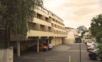 a city street with a large parking lot in front of a multi - story building , where several cars are parked at St Ives Apartments