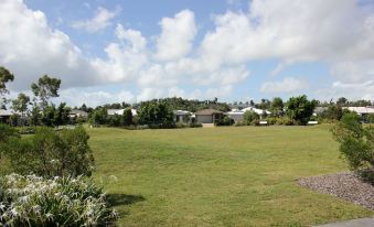 a large , open grassy field with trees and bushes in the background , and houses scattered across the landscape at Direct Collective - Breeze on Brightwater