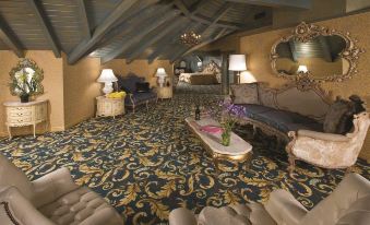 a luxurious living room with a carpeted floor , multiple couches , and a fireplace , along with a dining area in the background at Madonna Inn