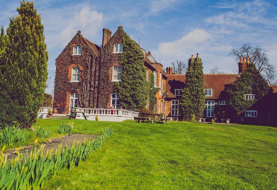 a large brick house with a red roof is surrounded by green grass and trees at Letchworth Hall