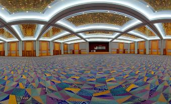 a large , empty room with a colorful carpet and a stage at the end of it at Renaissance Wind Creek Aruba Resort