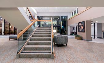 a modern office building with a staircase leading to the second floor , where a man is sitting on a couch at Hotel Ava Laredo