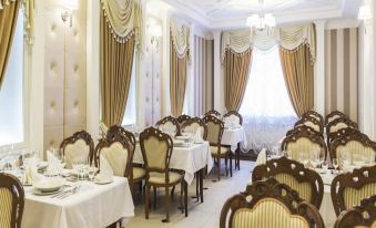 a large , elegant dining room with multiple tables and chairs set up for a formal meal at Metropol Hotel