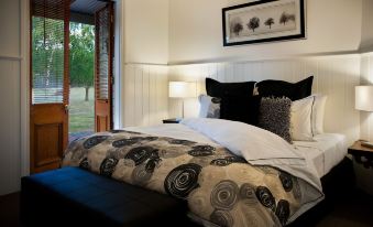 a large bed with a black and white comforter is in a bedroom with a door open to another room at The Gums