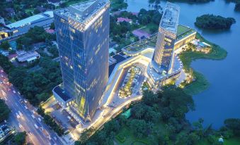 a city skyline at night , with buildings lit up and reflecting in the water below at Lotte Hotel Yangon