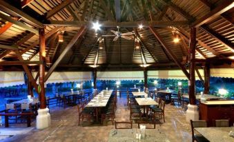 a large dining room with wooden tables and chairs arranged for a group of people at Mida Resort Kanchanaburi