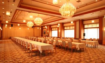 a large dining hall with long tables and chairs arranged for a formal event , surrounded by chandeliers at Zazan Minakami