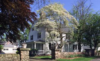 a large white house surrounded by trees and bushes , with a gate leading into the property at The Farmington Inn and Suites