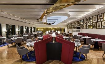 a large dining room with multiple tables and chairs arranged for a group of people to enjoy a meal together at The Oberoi Grand Kolkata