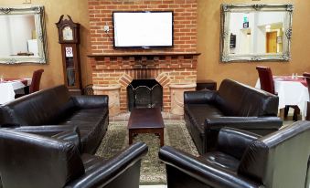 a living room with a brick fireplace , two leather couches , and a flat - screen tv mounted on the wall at Skylark Hotel