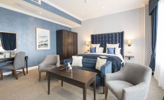 a modern hotel room with blue walls , white ceiling , and various furniture pieces including a bed , couch , and chairs at Cbh Hythe Imperial Hotel Golf and Spa