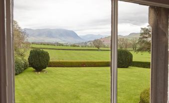 a view from a window , looking out at a lush green field with mountains in the background at Hundith Hill Hotel