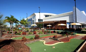 a building with a green lawn and umbrellas in front of it , under a clear blue sky at Mercure Sydney Liverpool