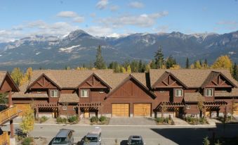 a group of small wooden houses with cars parked in front and mountains in the background at Whispering Pines