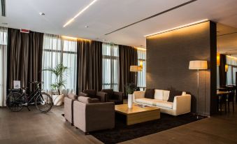 a modern living room with a large window , brown curtains , and white couches , along with a wooden coffee table at Quality Hotel San Martino