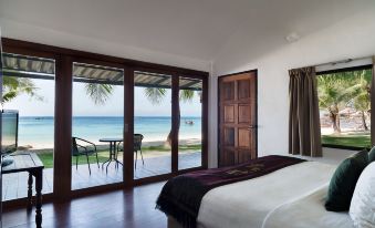 a bedroom with a large window overlooking the ocean and a bed with a black and white blanket at Mali Resort Pattaya Beach Koh Lipe
