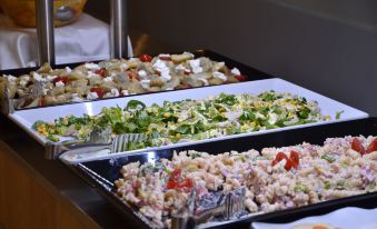 a variety of salads displayed on trays in a restaurant , with different types of salads and fruits at Belvedere Hotel