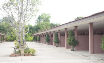 a row of buildings with red brick walls and white columns , surrounded by trees and grass at Rimmueng Resort