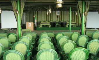 a large room with rows of green chairs arranged in an auditorium - style seating arrangement at Hotel Belveder