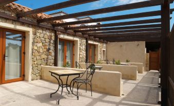 a patio area with stone walls , wooden beams , and outdoor furniture , under a blue sky at El Rancho