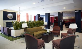 a spacious lobby with various seating options , including couches , chairs , and a dining table , as well as potted plants and artwork at Holiday Inn Birmingham - Hoover
