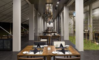 an empty restaurant with wooden tables and chairs , a chandelier hanging from the ceiling , and black tablecloths on the tables at Jetwing Lake