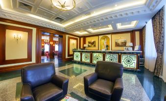 a hotel lobby with a marble floor , two black chairs , and a reception desk in the background at Hotel Parus