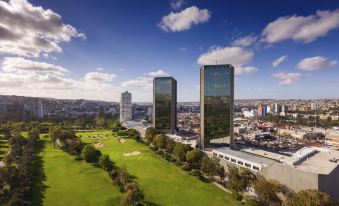 an aerial view of a city with two tall buildings in the background , surrounded by a green park and trees at Grand Hotel Tijuana