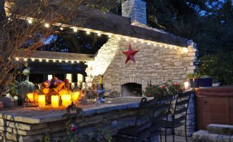 a brick outdoor kitchen with a fireplace and a red star on the wall is lit up at night at Southern Rose Ranch
