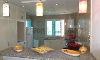 a well - equipped kitchen with stainless steel appliances , including a refrigerator , oven , and microwave , as well as various utensils and bowls at Rahma