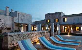 a modern house with a stone exterior and wooden deck , surrounded by blue and white striped lounge chairs at Borgo Sentinella