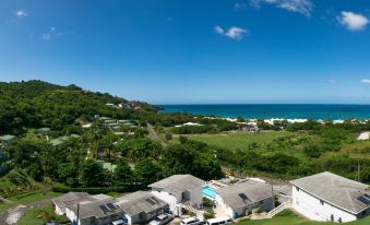 a picturesque view of a beachfront community with houses , trees , and the ocean in the background at Siesta Hotel